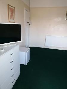 Una sala de estar con televisión y una alfombra verde. en Central location, en Staines upon Thames