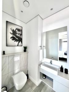 a white bathroom with a toilet and a sink at The Trilogy Collection Luxury One Bedroom in Pretoria +16 photos