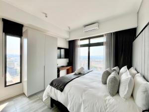 a bedroom with a large white bed with large windows at The Trilogy Collection Luxury One Bedroom in Pretoria