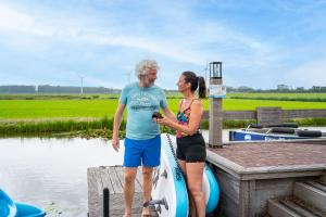 a man and a woman standing on a dock with a boat at Park Westerkogge in Berkhout +21 photos