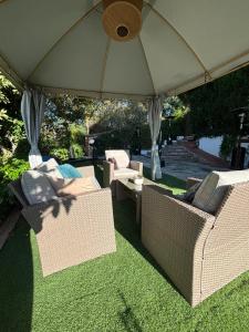 a group of wicker chairs and tables under an umbrella at Aya House in Barcelona