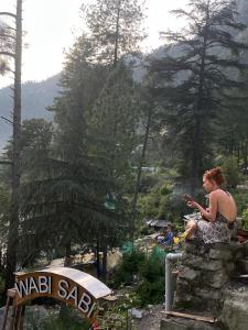 a woman sitting on top of a stone wall at Wabi Sabi Hostel in Kasol