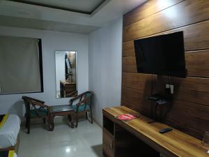 a room with a television and a desk with a chair at Hotel Sr Residency Jail Road Tilak Nagar in New Delhi