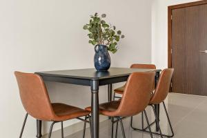 a table with a vase on top of it with chairs at Silkhaus Premier 2BR Apartment in Marina Bay in Mushayrib