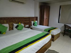 a bedroom with two beds with green and white sheets at Hotel Sr Residency Jail Road Tilak Nagar in New Delhi