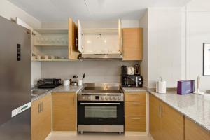 a kitchen with wooden cabinets and a stove top oven at Silkhaus Premier 2BR Apartment in Marina Bay in Mushayrib