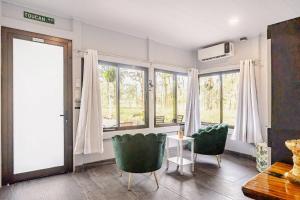 a living room with green chairs and a table and windows at Pura Vidaville - Toucans Nest in El pilon