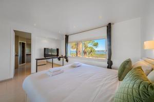 una camera da letto con un grande letto bianco con una grande finestra di Canal House - Lake View - ParkingAir Conditioning a Palavas-les-Flots