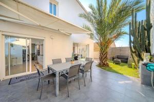 un patio con tavolo, sedie e palma di Canal House - Lake View - ParkingAir Conditioning a Palavas-les-Flots