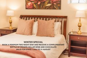 een slaapkamer met een bed met twee nachtkastjes en twee lampen bij Protea Garden Cottage in Stellenbosch