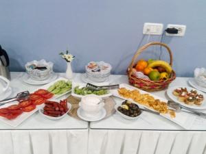 a table with plates of food and a basket of fruit at Capital Tirana Hotel Bruçi in Tirana