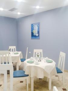 a dining room with white tables and white chairs at Capital Tirana Hotel Bruçi in Tirana