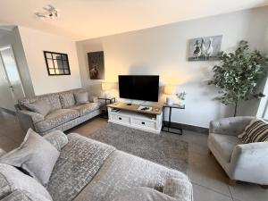 a living room with two couches and a flat screen tv at Marigold Cottage in Brockenhurst