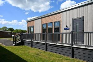 a building with a fence next to a grass field at Sunniva Lodge in Malton