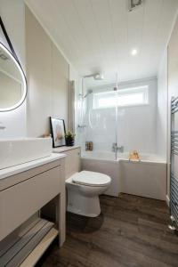 a white bathroom with a toilet and a bath tub at Sunniva Lodge in Malton