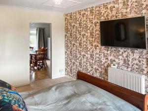 a bedroom with a tv on a wall with floral wallpaper at The Room Next Door in Flemingston