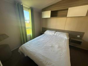 a bedroom with a white bed and a window at Salty Breezes in Ingoldmells