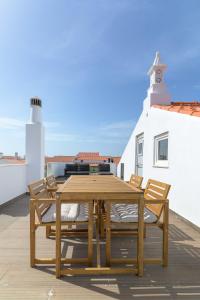 a wooden table and chairs on a patio with a lighthouse at Esteva CountryHouse in Rogil