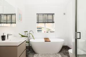 a white bathroom with a tub and a sink at Pass the Keys Modern family home Garden Parking in Bourton on the Water +21 photos