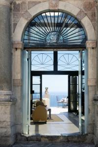 Une porte ouverte s'ouvre sur une terrasse offrant une vue sur l'océan. dans l'établissement Hotel Metropole Taormina, à Taormine 121 autres photos
