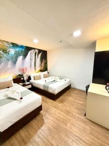 two beds in a room with a painting on the wall at Swiss Hotel at City Centre in Kuala Lumpur