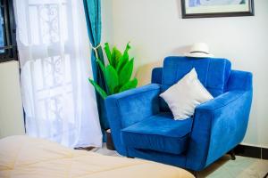 a blue chair with a white pillow in a room at Toria Homes in Namulanda