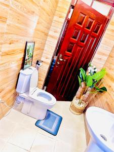 a bathroom with a toilet and a red door at Toria Homes in Namulanda +11 photos