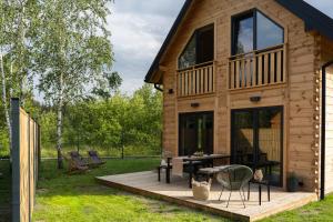a cabin with a deck with a table and chairs at Polna Osada Nadkole in Nadkole