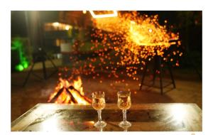 two glasses of wine sitting next to a fire at Periyar Heritage Homes in Thekkady