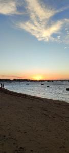 a sunset on the beach with boats in the water at Espacio chill hostel in Búzios