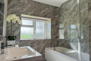 a bathroom with a tub and a sink and a window at Marrington Lodge in Chirbury +25 photos
