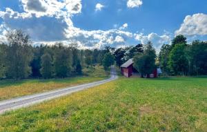 an empty road leading to a red barn in a field at 2 Bedroom Amazing Apartment In Flisby in Ägersryd +15 photos