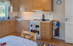 a kitchen with wooden cabinets and a stove and a table at 2 Bedroom Amazing Apartment In Flisby in Ägersryd