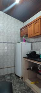 a kitchen with a white refrigerator and wooden cabinets at Espacio chill hostel in Búzios