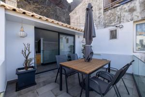 a patio with a wooden table and chairs and an umbrella at No Stress House in Paul do Mar