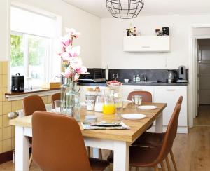 a kitchen with a wooden table with chairs and flowers at The Holidayhouse in Loon op Zand