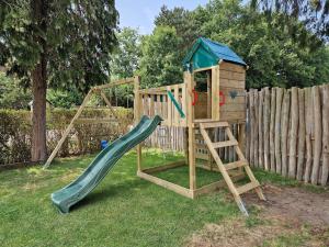 a wooden playground with a slide and a ladder at The Holidayhouse in Loon op Zand