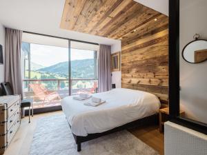Un dormitorio con una cama y una ventana grande. en Lodge 4****, 8 voyageurs, Sauna, Balcon, Accès internet, Parking - FR-1-304-217, en La Clusaz