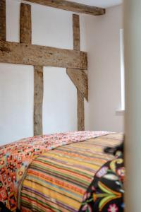 a bed with a wooden headboard in a room at Stylish 2-bed 16th-century apartment in Petersfield town centre, in Petersfield