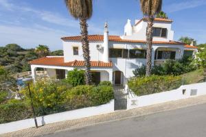 a white house with palm trees in front of it at Villa Curva do Monte by Villa Plus in Carvoeiro