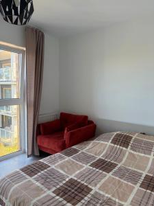 a bedroom with a red bed and a window at Apartament nad Wartą Śrem in Śrem