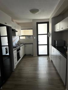 a kitchen with white cabinets and a large door at Fifi Self catering in Ongwediva