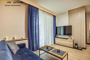 a living room with a blue couch and a tv at Baltic Apartments - Matejki 17 in Świnoujście