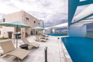 a pool on the roof of a building with chairs and umbrellas at 모어댄 속초해변점 in Sokcho