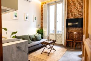 ein Wohnzimmer mit Sofa und Fernseher in der Unterkunft Uma Suites Fuencarral in Madrid