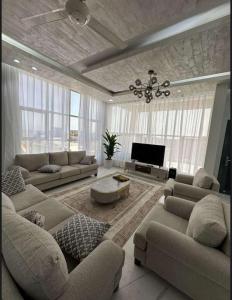 a large living room with couches and a television at Santorini chalet شاليه سانتوريني in Ad Daffah