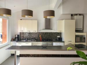 a kitchen with white cabinets and a counter top at Appartement lumineux à deux pas du port, avec terrasse in La Ciotat +7 photos