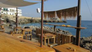 a group of tables and benches next to the water at Monolocale Santa Caterina in Santa Caterina di Nardò