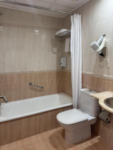 a bathroom with a toilet and a tub and a sink at Hotel Plaza Inn in Figueres +52 photos