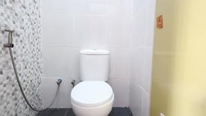 a bathroom with a white toilet in a stall at Omah Sewu Sakura By Reccoma in Surabaya